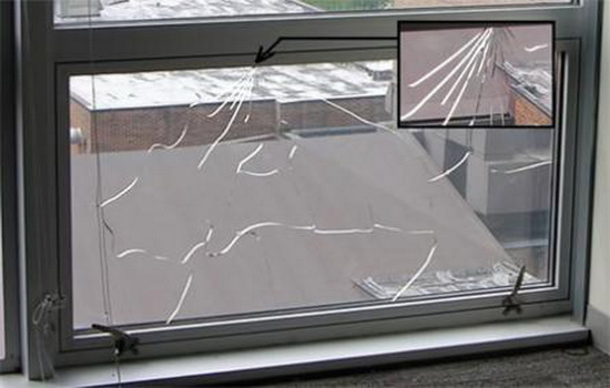 Лопнувшее окно с трещинами на стекле